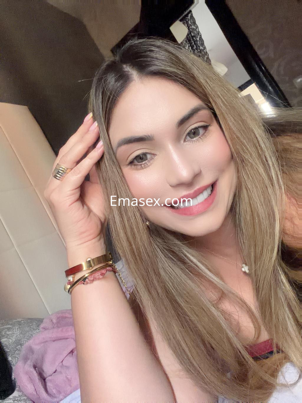 Escort en Bilbao con cabello largo y lacio, sonriente, luciendo un atuendo casual en un ambiente acogedor.