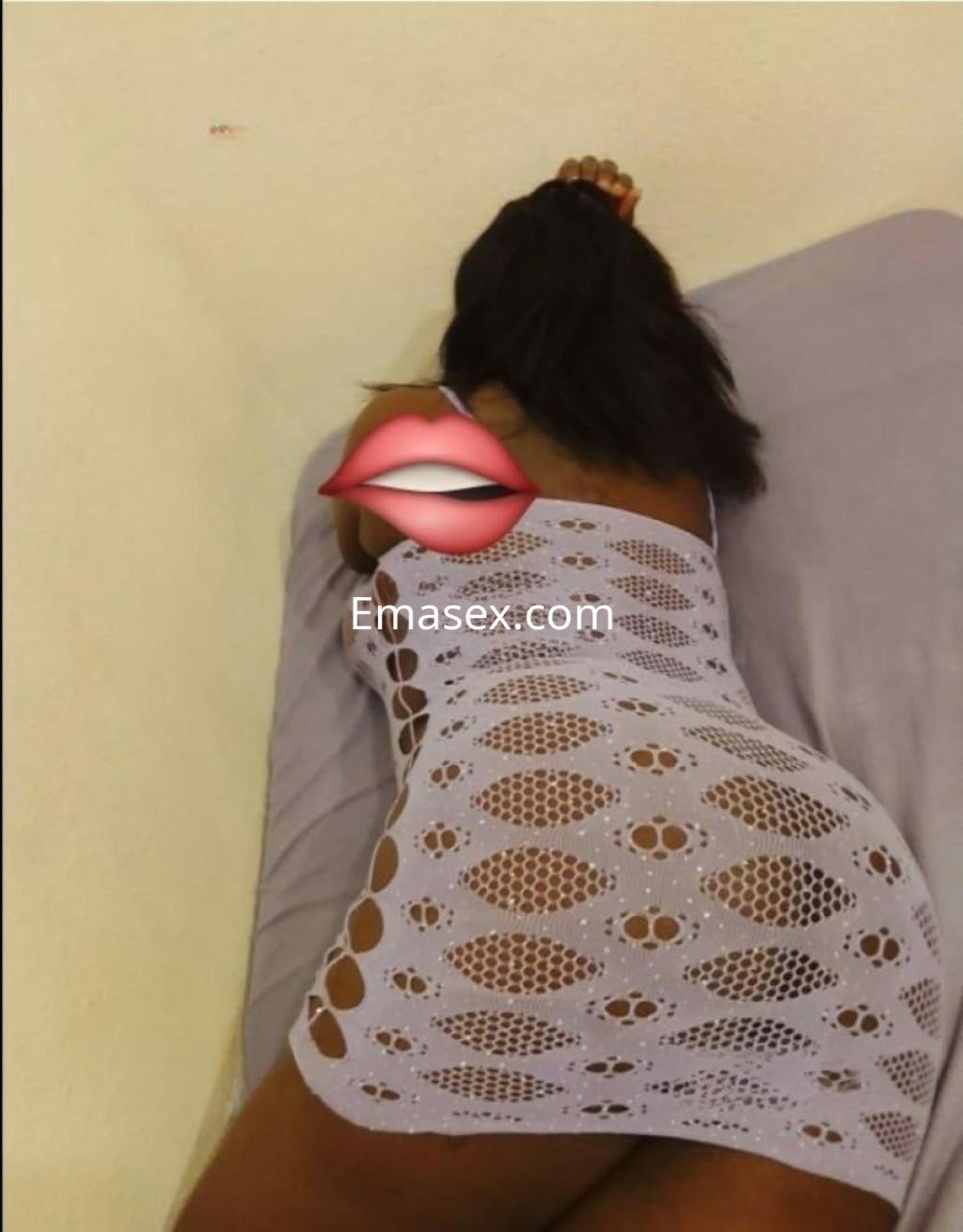 Escort en Toledo con cabello oscuro, vistiendo un vestido de encaje claro, posando sobre una cama.