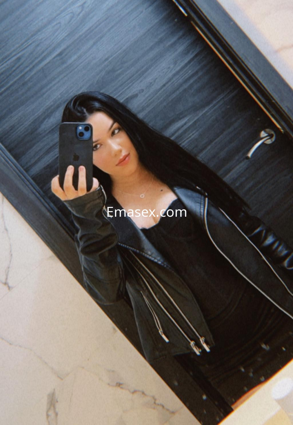 La puta se toma una selfie frente a un espejo, vistiendo un corsé negro y una chaqueta de cuero en Gijón.