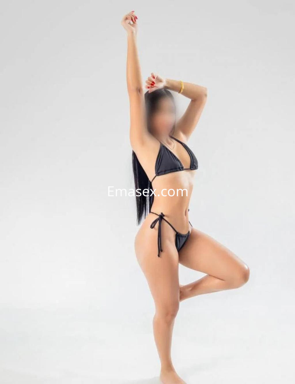 Puta en Valladolid posando con un bikini negro, mostrando su figura esbelta y cabello largo, sobre fondo blanco.
