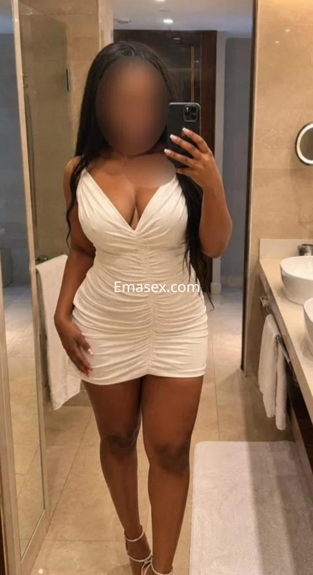 Escort en Las Palmas luce un vestido blanco ajustado que acentúa su figura, posando en un baño elegante.