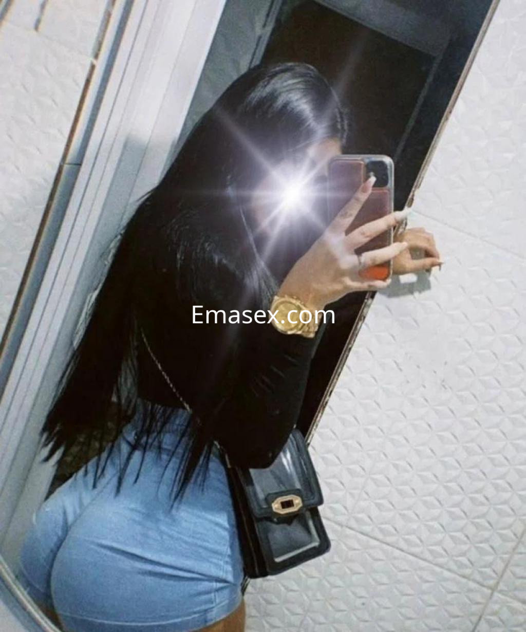 Puta de Badajoz viste un ajustado top negro y shorts de mezclilla, mientras se toma una selfie en el espejo.