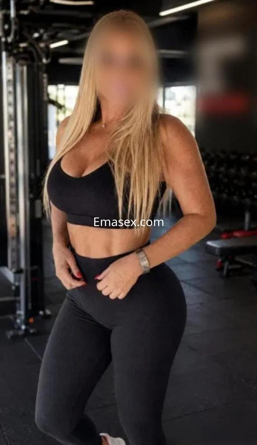 Escort en Zamora con cabello largo y rubio, vestida con top negro y leggings ajustados en un gimnasio.