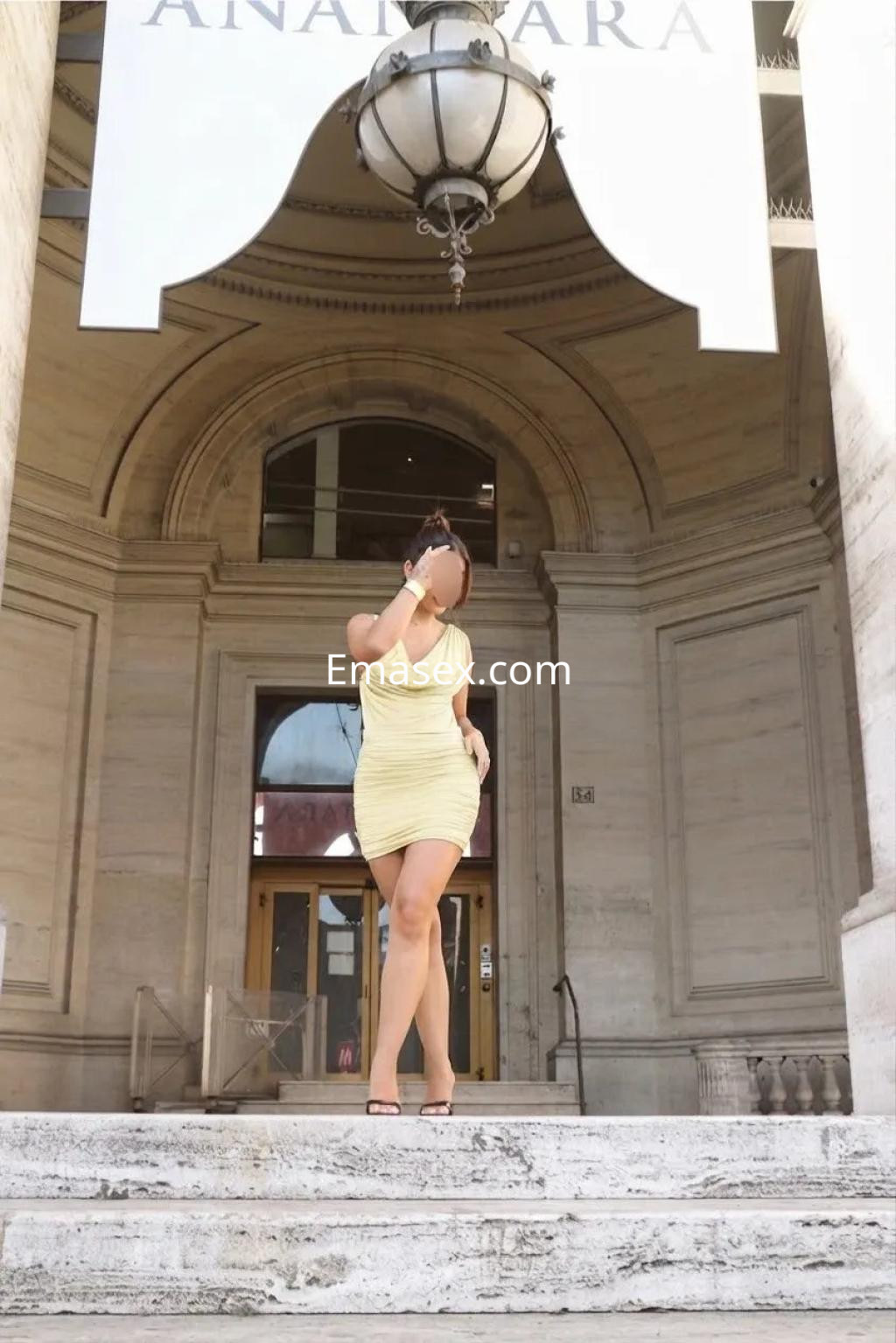 La puta luce un vestido amarillo ajustado mientras posa en las escaleras de un edificio en Sevilla.