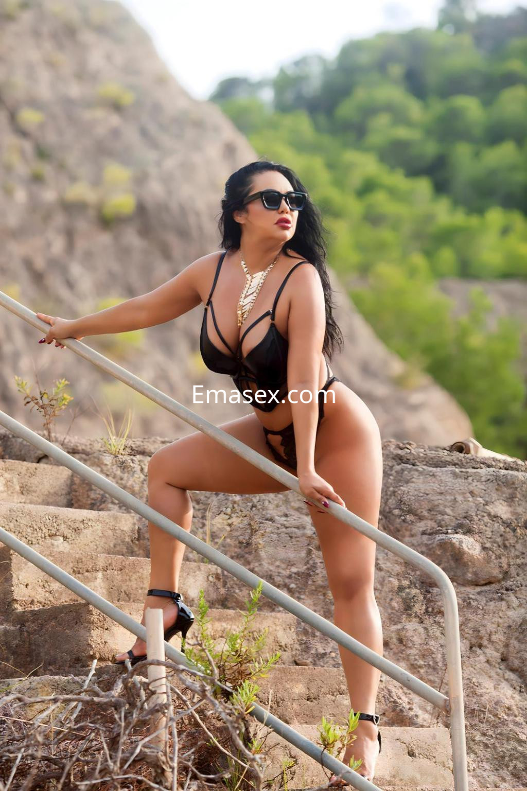 La puta posa en un entorno natural, con un traje de baño negro y gafas de sol, destacando su figura en Tenerife.