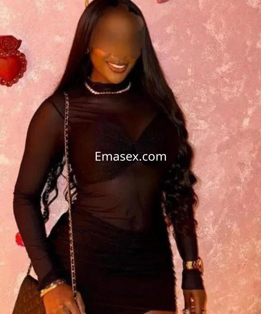 Puta en Zamora viste un vestido negro transparente que resalta su figura, con cabello largo y ondulado.