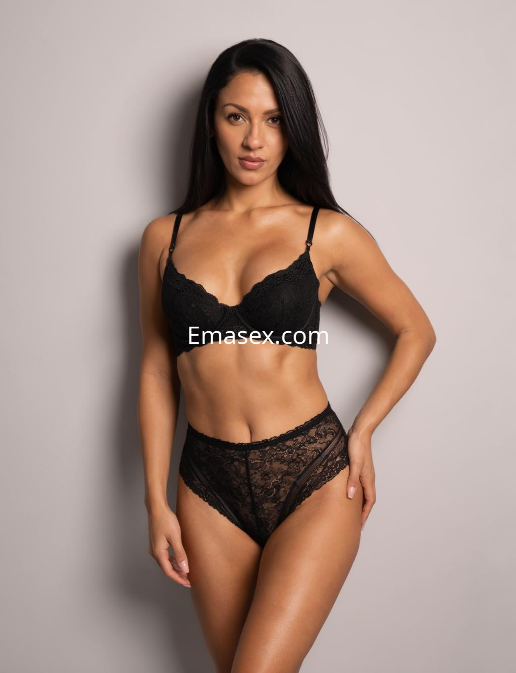 Escort en Vigo posando frente a un fondo neutro, vistiendo un conjunto de lencería negra y mostrando una expresión segura.