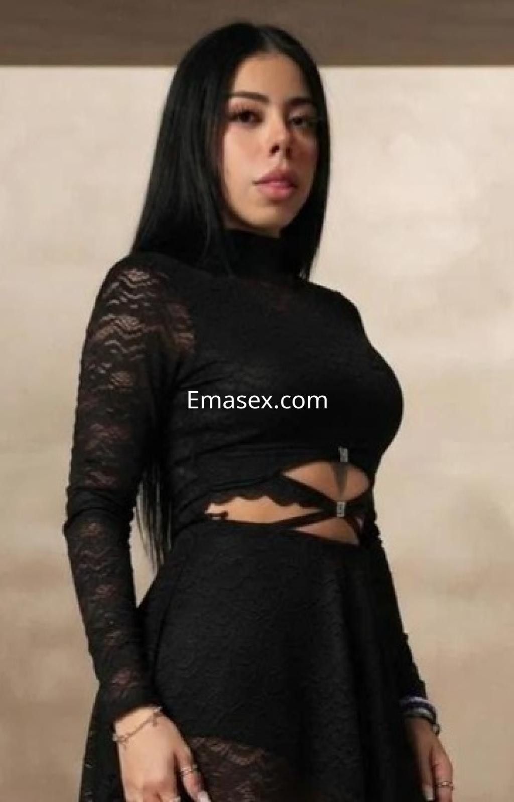 Puta en Las Palmas con vestido negro de encaje y detalles cut-out, posando con una expresión intrigante.