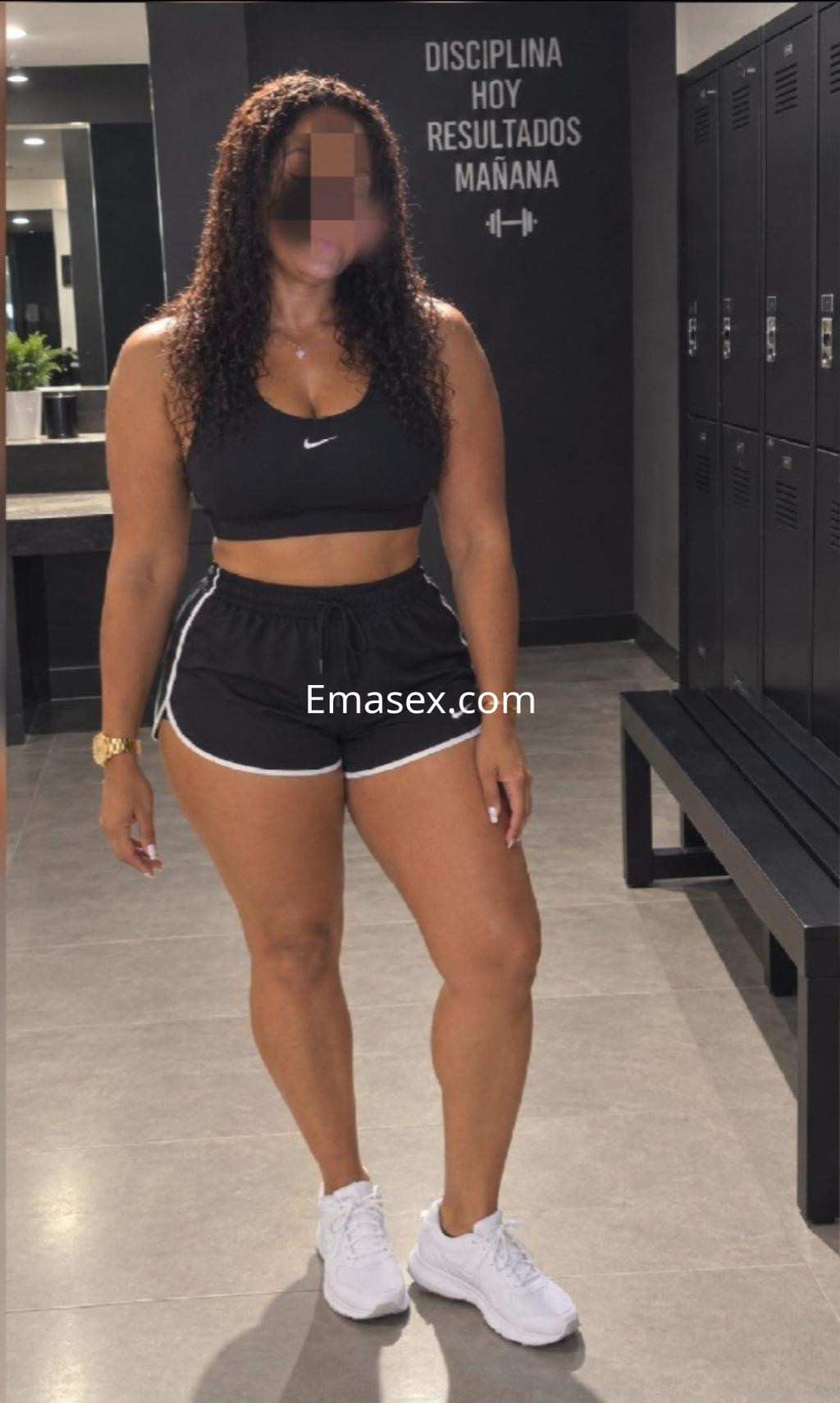 Escort en Pamplona con cabello rizado y oscuro, vestida con un top negro y shorts deportivos.