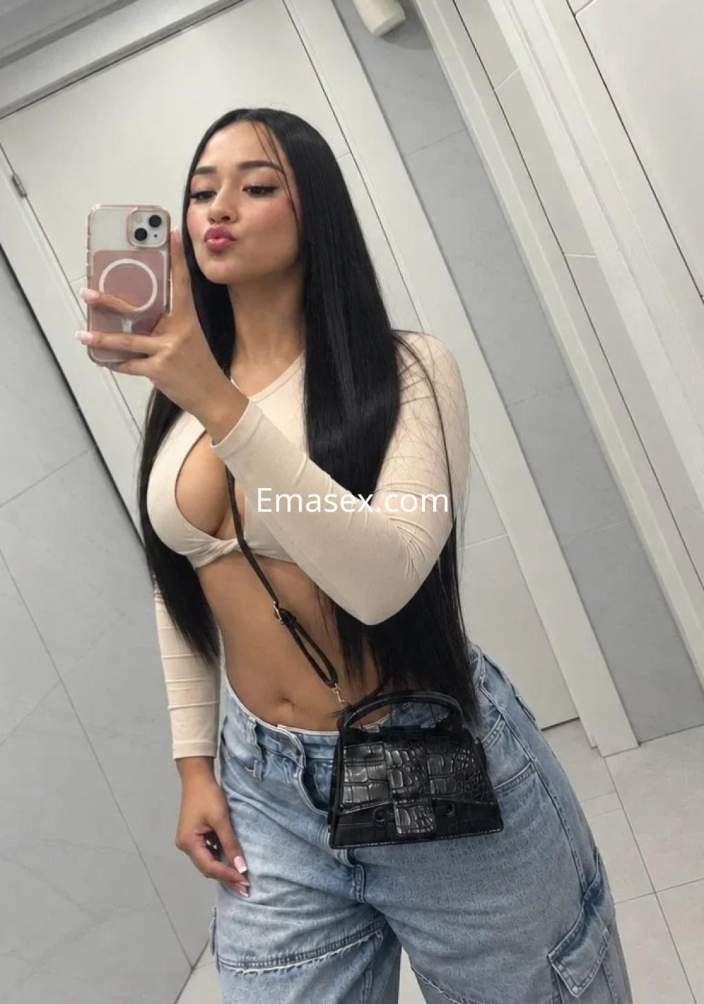 Puta en Vigo, luciendo un top claro que deja al descubierto su abdomen y pantalones anchos, posando en un espejo.