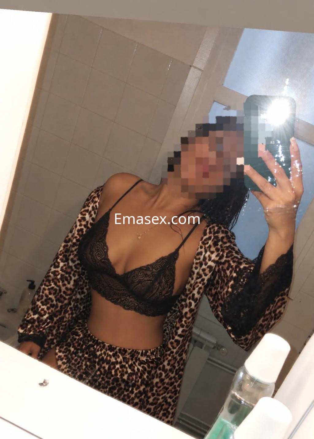 La puta en Santiago posa frente al espejo con lencería negra y un kimono de estampado de leopardo.