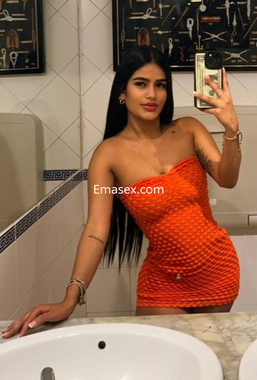 La puta posa en un baño, vistiendo un vestido corto naranja y mostrando su cabello largo y lacio en Vigo.