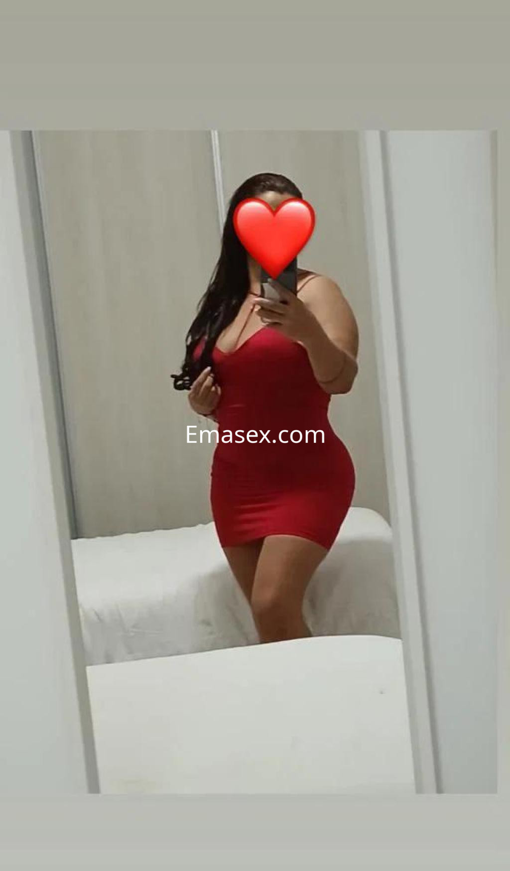 La puta en Las Palmas luce un vestido rojo ajustado mientras se toma una selfie en un espejo.