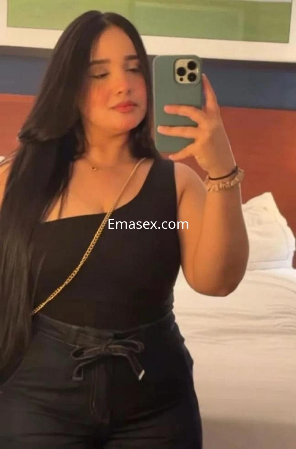 Escort en Sevilla con cabello largo y lacio, vestida con una blusa negra y pantalones oscuros, posando en un hotel.