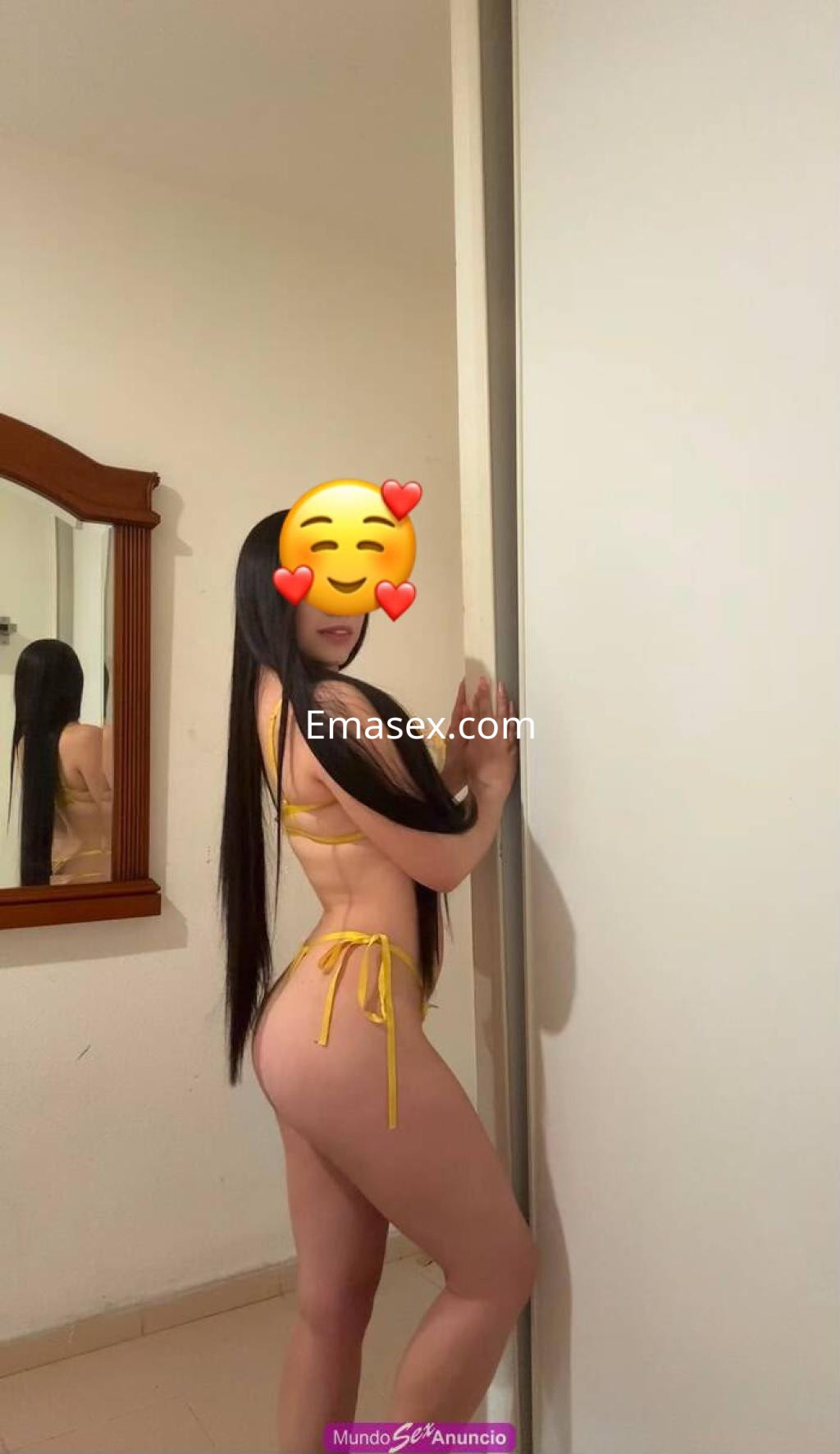 Puta en Valladolid posando de lado, vistiendo un bikini amarillo con tirantes, en un entorno sencillo.