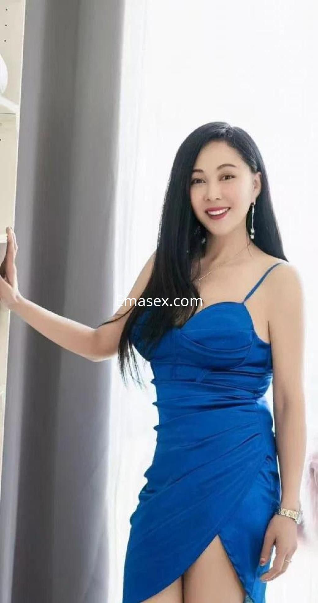 La puta luce un vestido azul ajustado y elegante, con el cabello largo y lacio, en un entorno luminoso de Lugo.