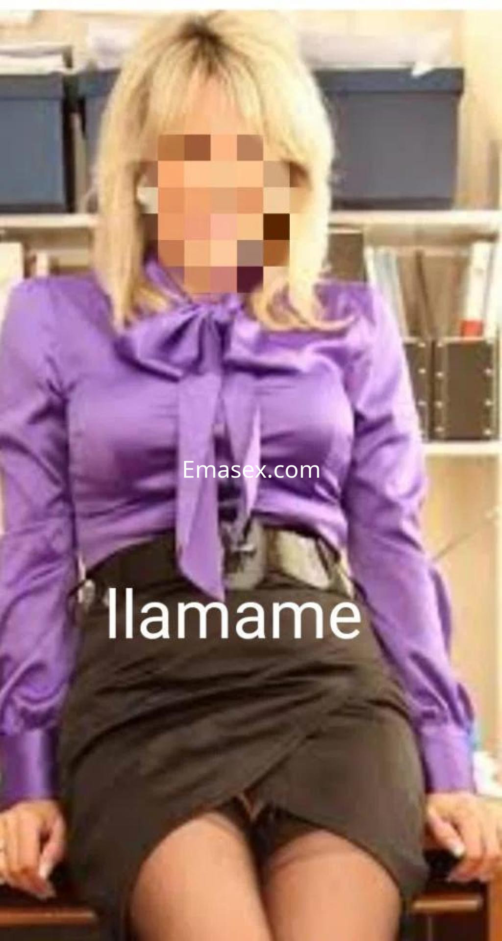 Escort en Coruña con blusa morada y falda negra, sentada en una oficina, mostrando un look elegante y profesional.
