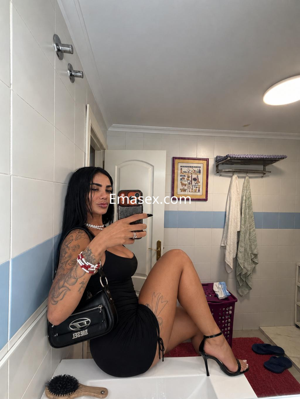 La puta en Zaragoza lleva un vestido negro ajustado, posando sobre el lavabo mientras se toma una selfie.