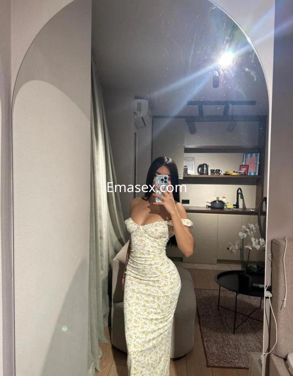 Escort en Lleida, luciendo un vestido ajustado de flores con escote y mangas cortas en un entorno moderno.