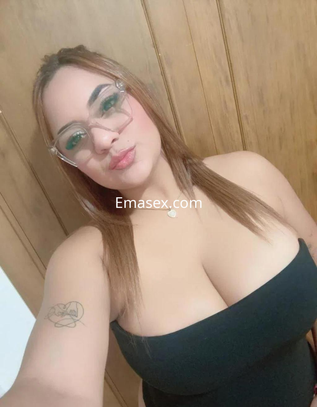 Puta en Cádiz, con cabello castaño y lacio, usando un vestido negro ajustado y gafas claras, posando sonriente.