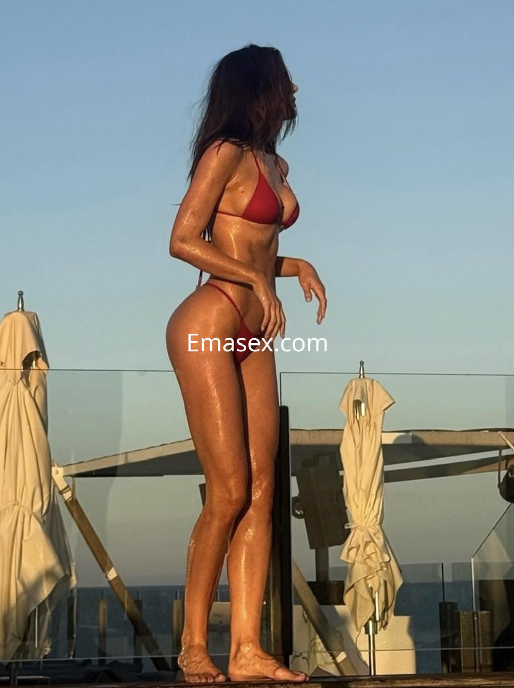 Escort en Donosti luciendo un bikini rojo, con piel bronceada y cabello suelto, en un entorno al aire libre.