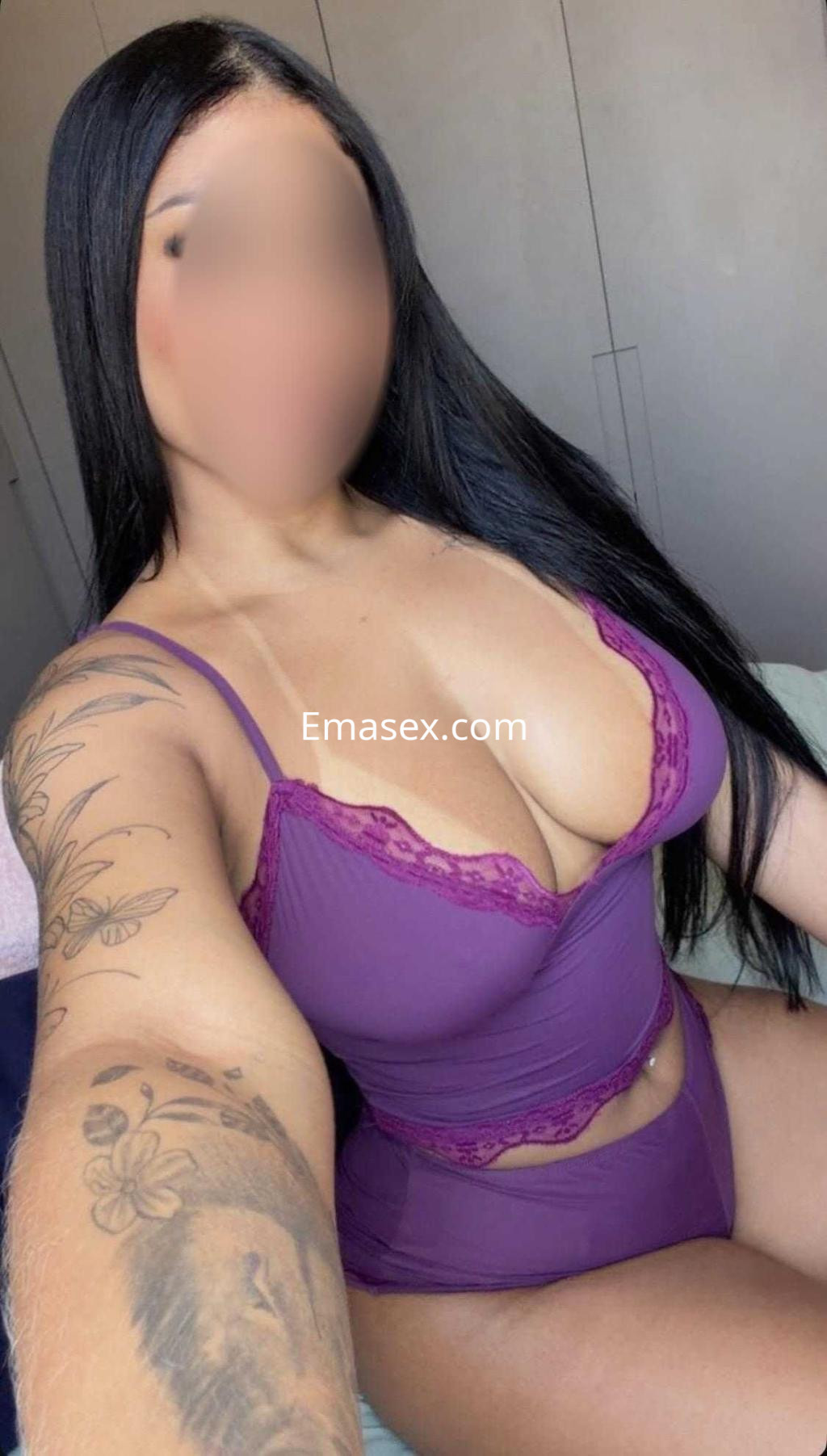 Puta en Valladolid posa con lencería morada, mostrando su piel y tatuajes en un entorno moderno.