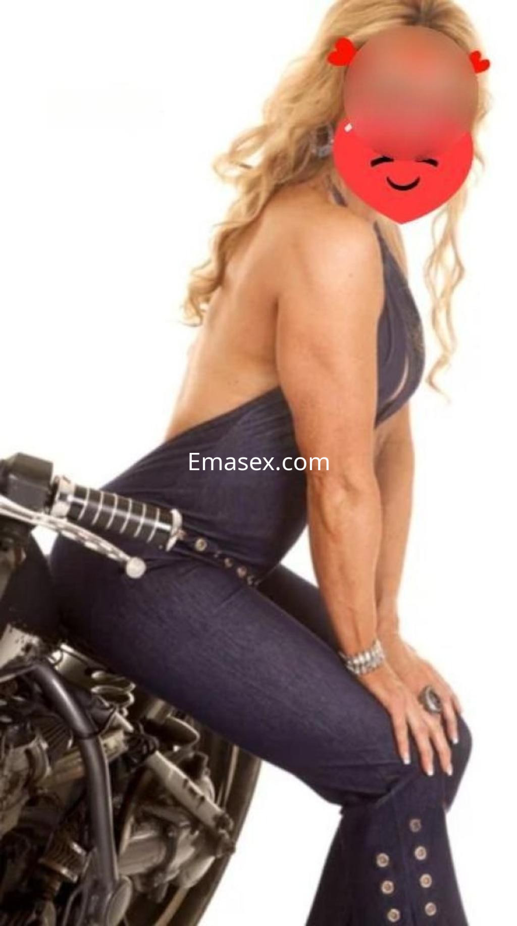 Puta con cabello rubio sentada sobre una moto, vistiendo un mono de mezclilla ajustado en Málaga.