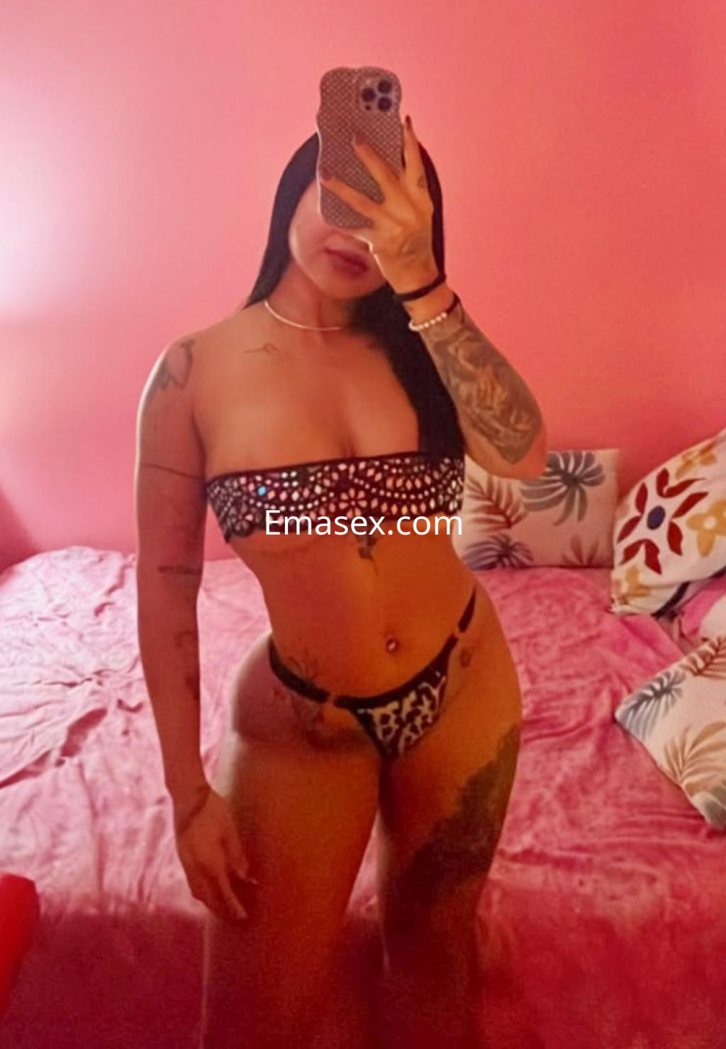 Puta en Vitoria con bikini de tirantes y estampado, mostrando su figura en un ambiente de tonos rosados.