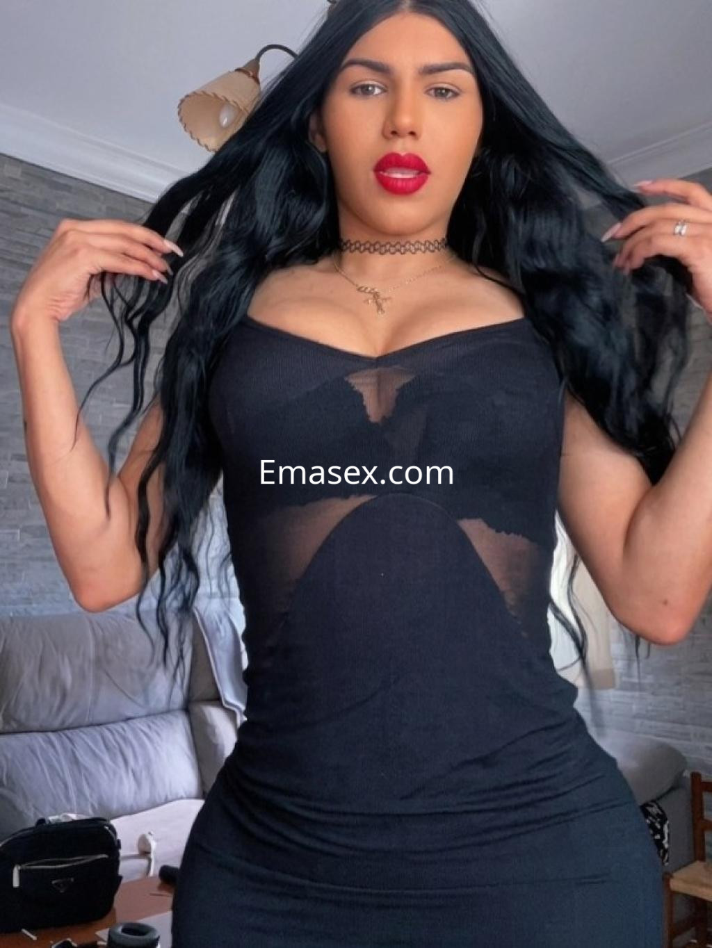 Escort trans en Gijón con cabello negro y largo, luciendo un vestido negro ajustado y posando con confianza.