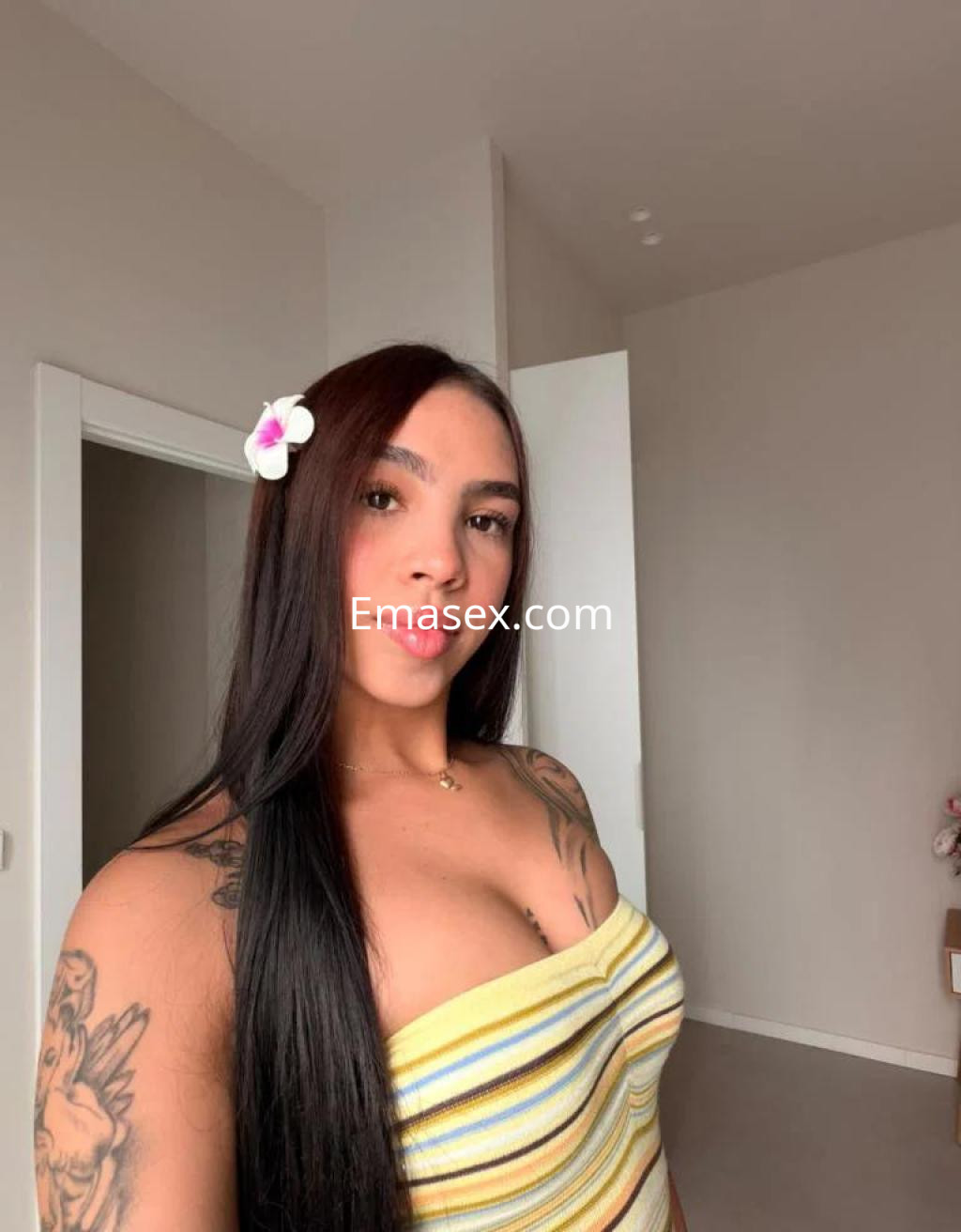 Escort en Zamora, con cabello largo y lacio, lleva una blusa sin mangas a rayas y una flor en el cabello.