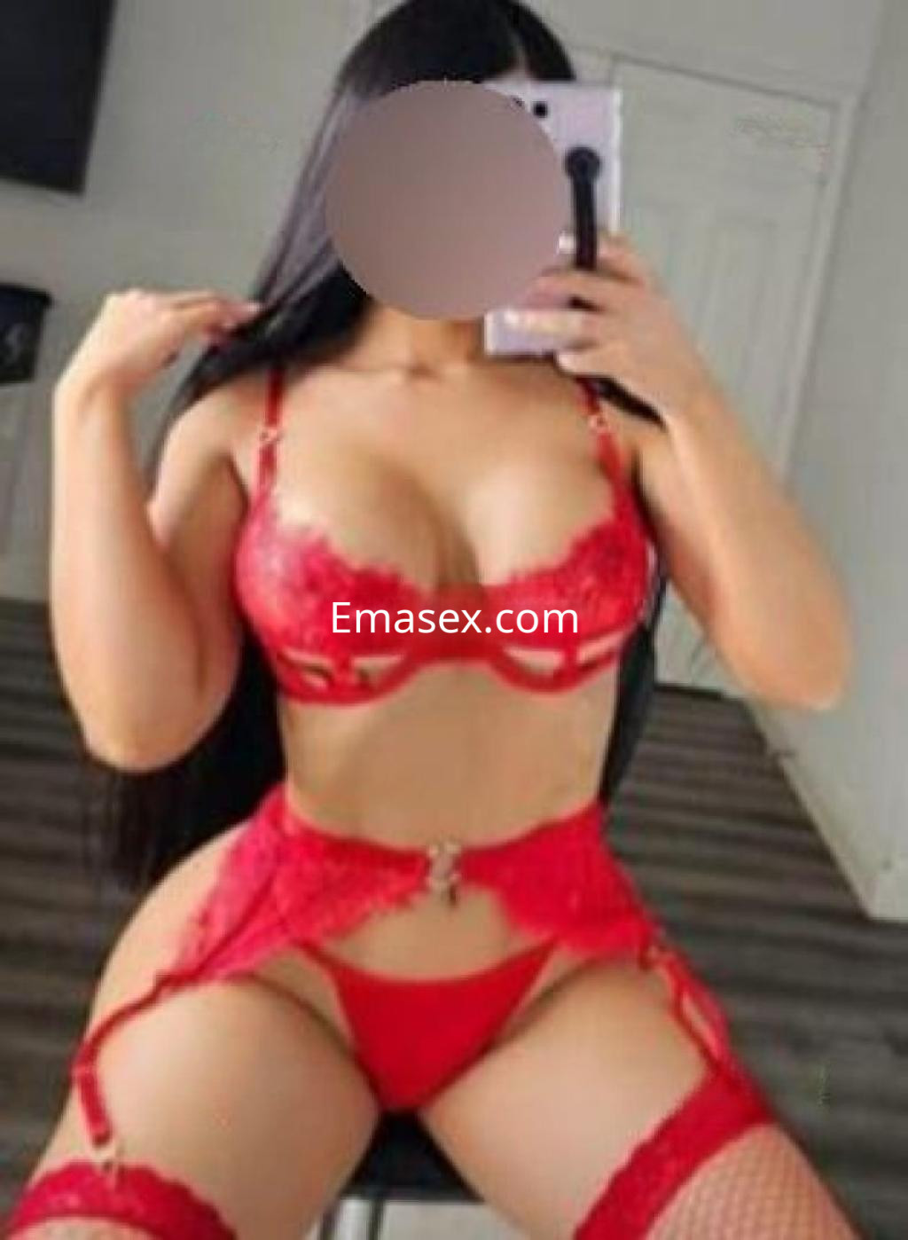 Escort en Málaga posando con lencería roja, cabello largo y liso, en un entorno interior con suelo de madera.