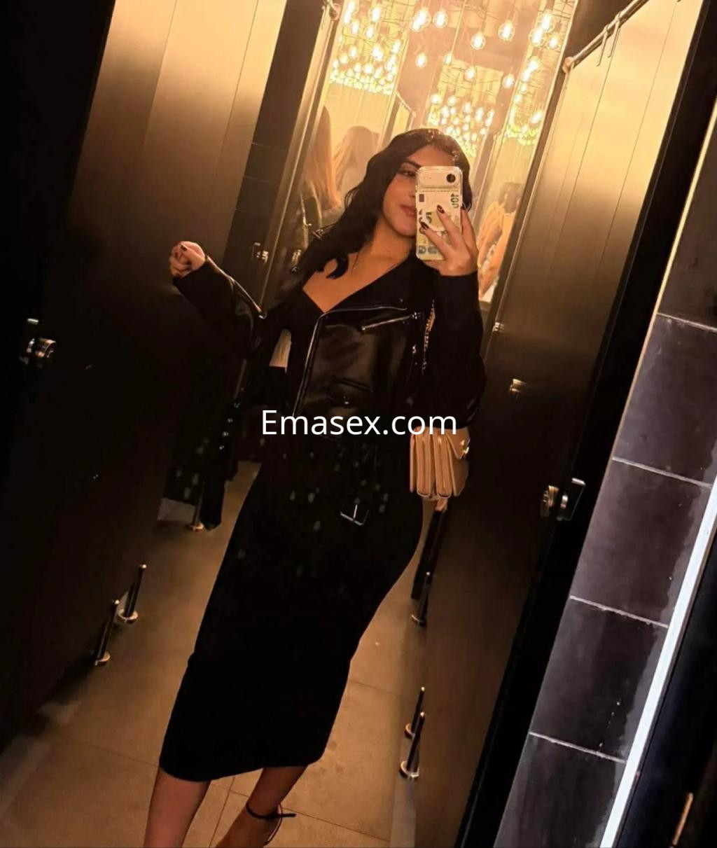 Escort en Coruña con cabello oscuro y ondulado, vistiendo una chaqueta de cuero y una falda larga negra.