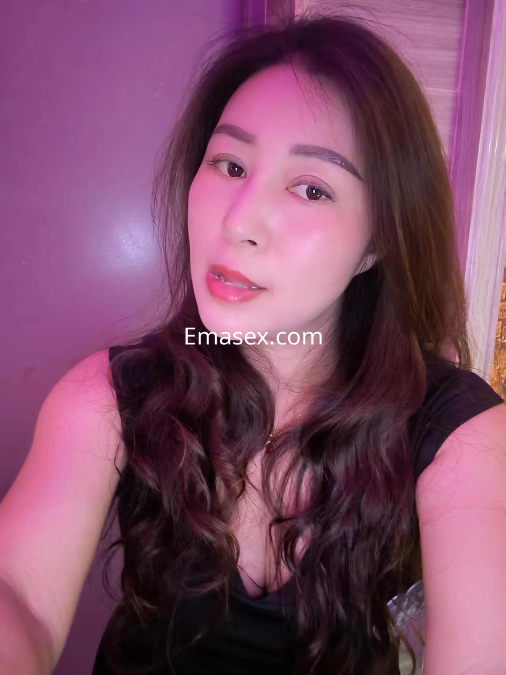 Escort en Albacete con cabello largo y ondulado, viste una blusa oscura y posa con una expresión suave.
