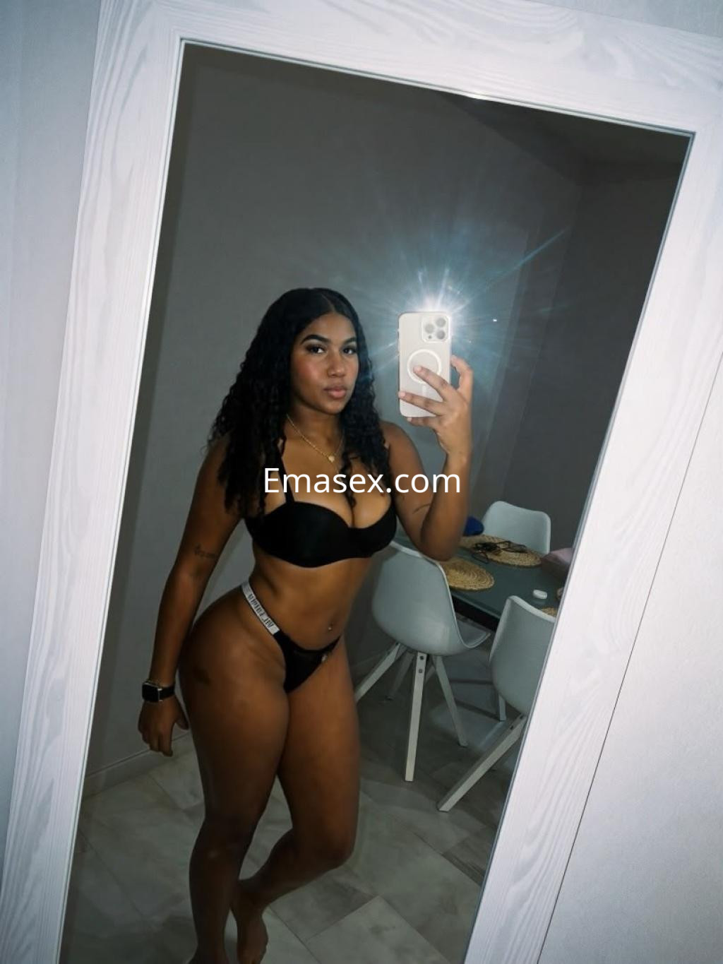 Escort con cabello rizado y oscuro, viste un bikini negro y se refleja en un espejo en Córdoba.