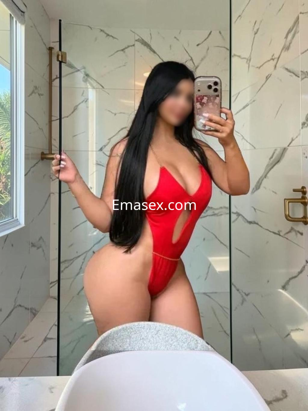 Puta en León posa en el baño con un traje de baño rojo de corte atrevido, mostrando su figura en un ambiente elegante.