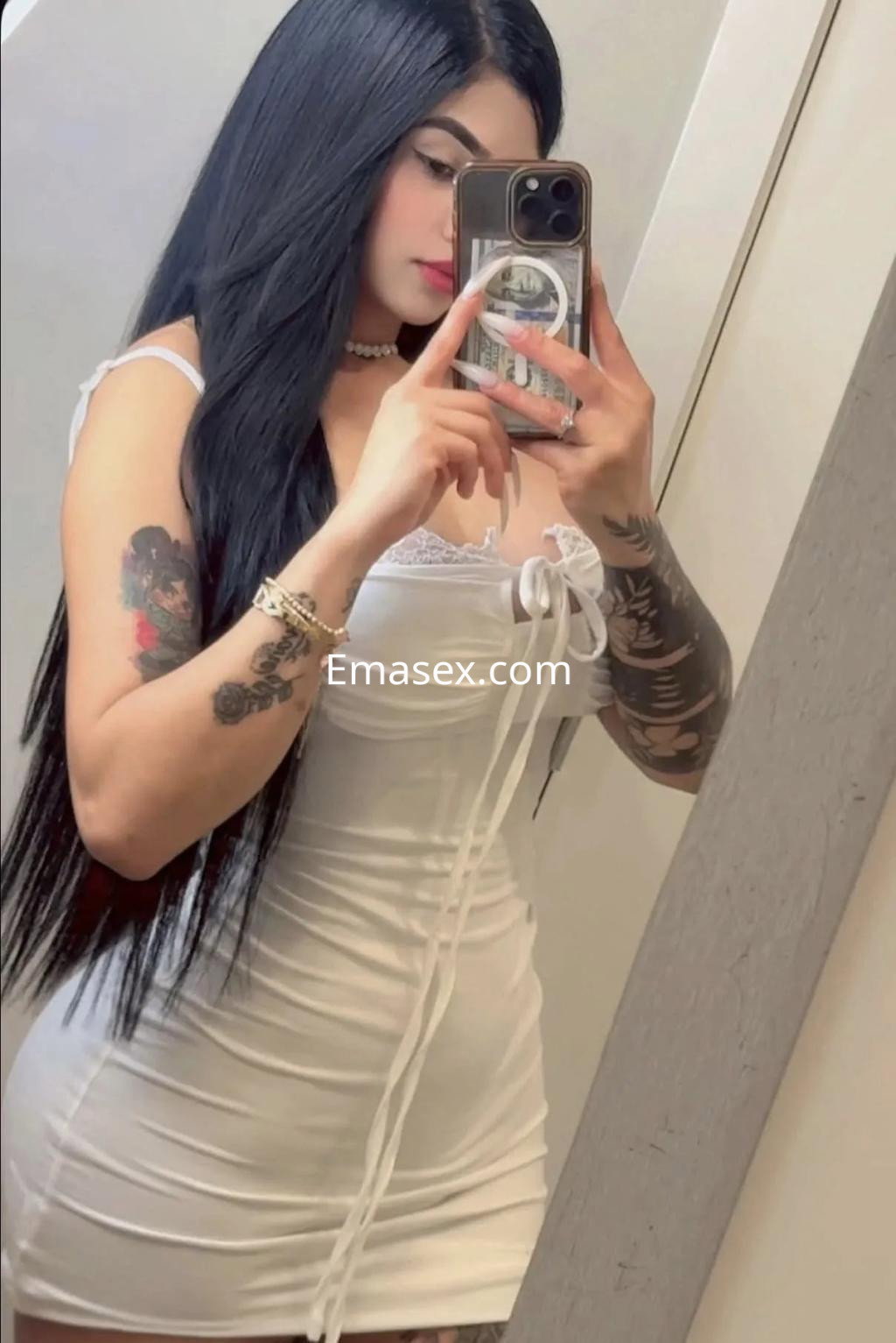 Puta de Burgos con cabello largo y lacio, viste un vestido blanco ajustado y se toma un selfie en el espejo.