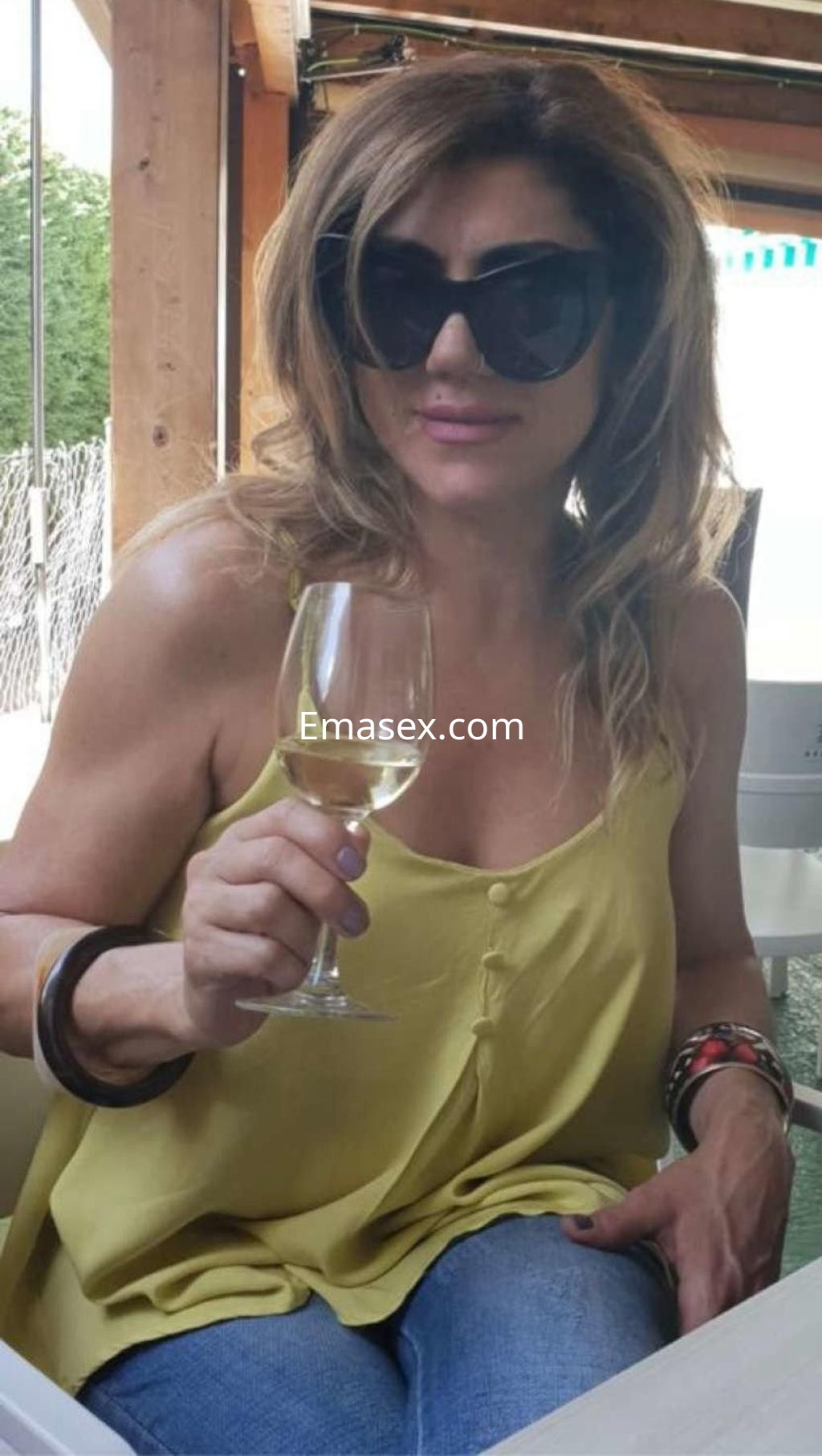 Puta en Toledo con cabello largo y lacio, usando una blusa amarilla y sosteniendo una copa de vino.
