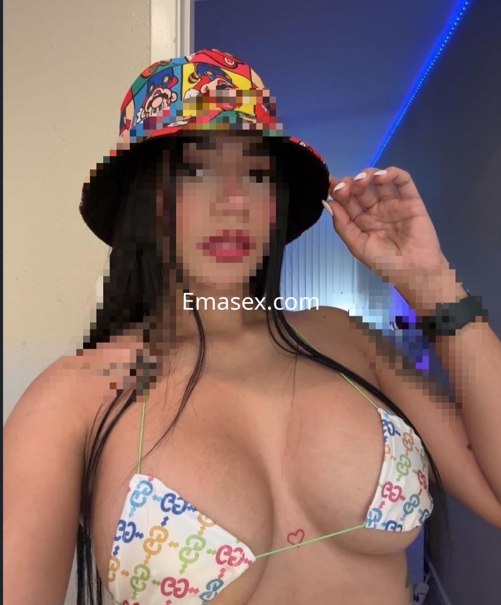 Escort en Valladolid se retrata con un bikini colorido y un sombrero, luciendo su cabello largo y lacio.