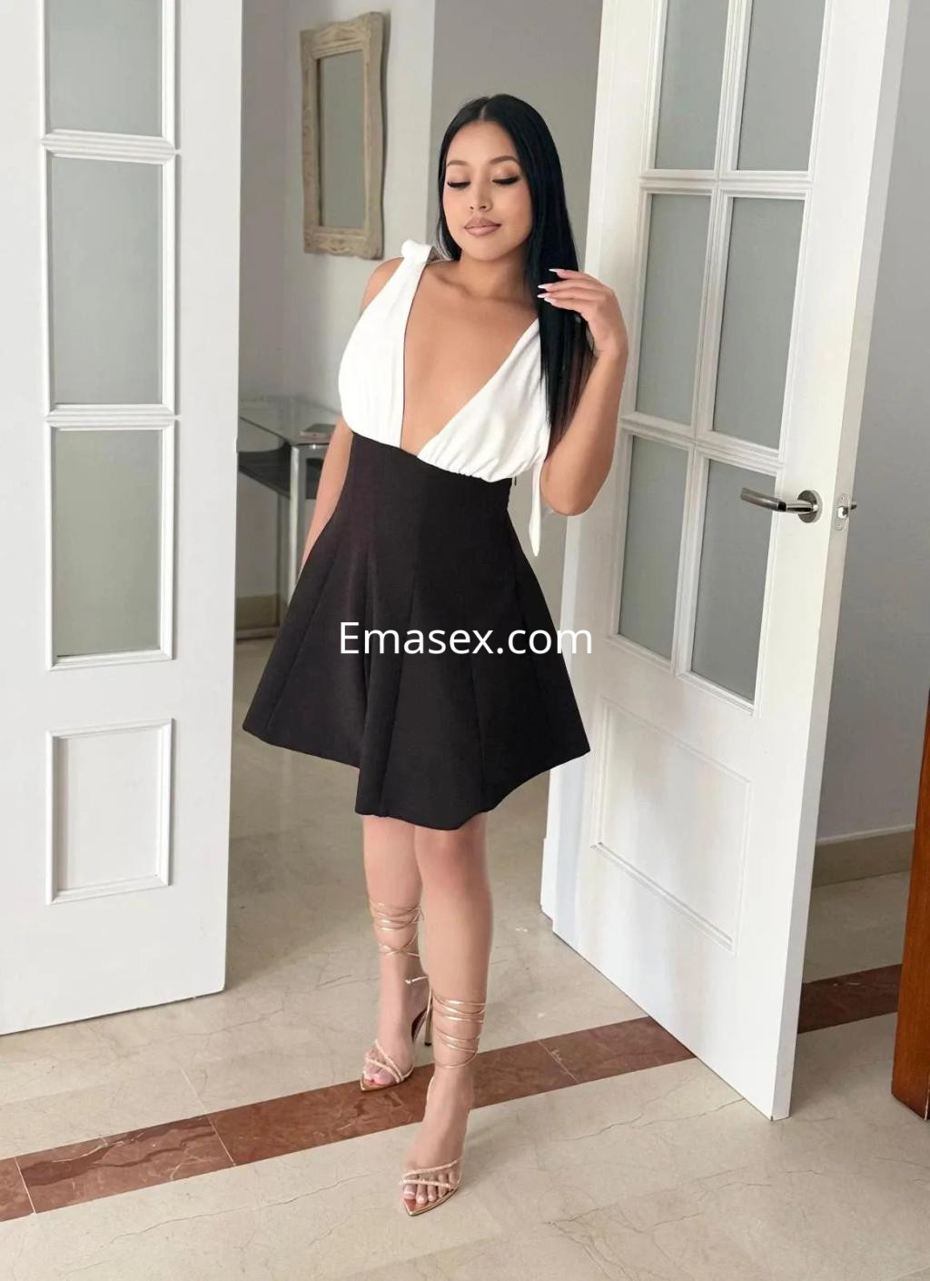 La escort en Málaga luce un vestido de corte ajustado en blanco y negro, con tacones transparentes.