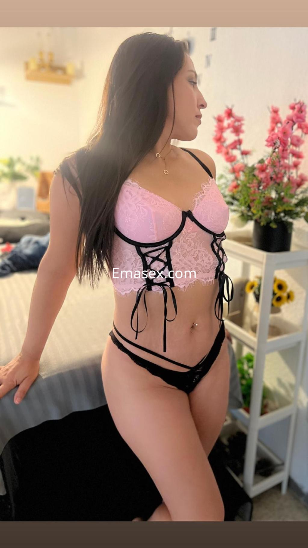 La puta luce un conjunto de lencería rosa y negro, posando con elegancia en un ambiente acogedor en Pontevedra.