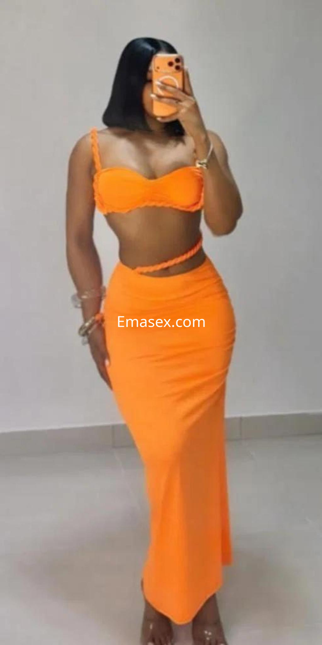 Puta en Málaga viste un conjunto de dos piezas naranja, mostrando una figura esbelta y elegante.