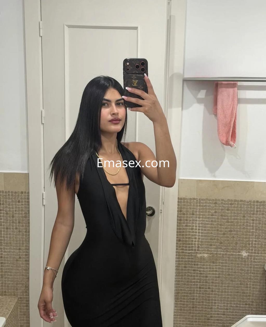Puta en Cádiz posando con un vestido negro ajustado, de escote pronunciado y cabello largo y lacio.