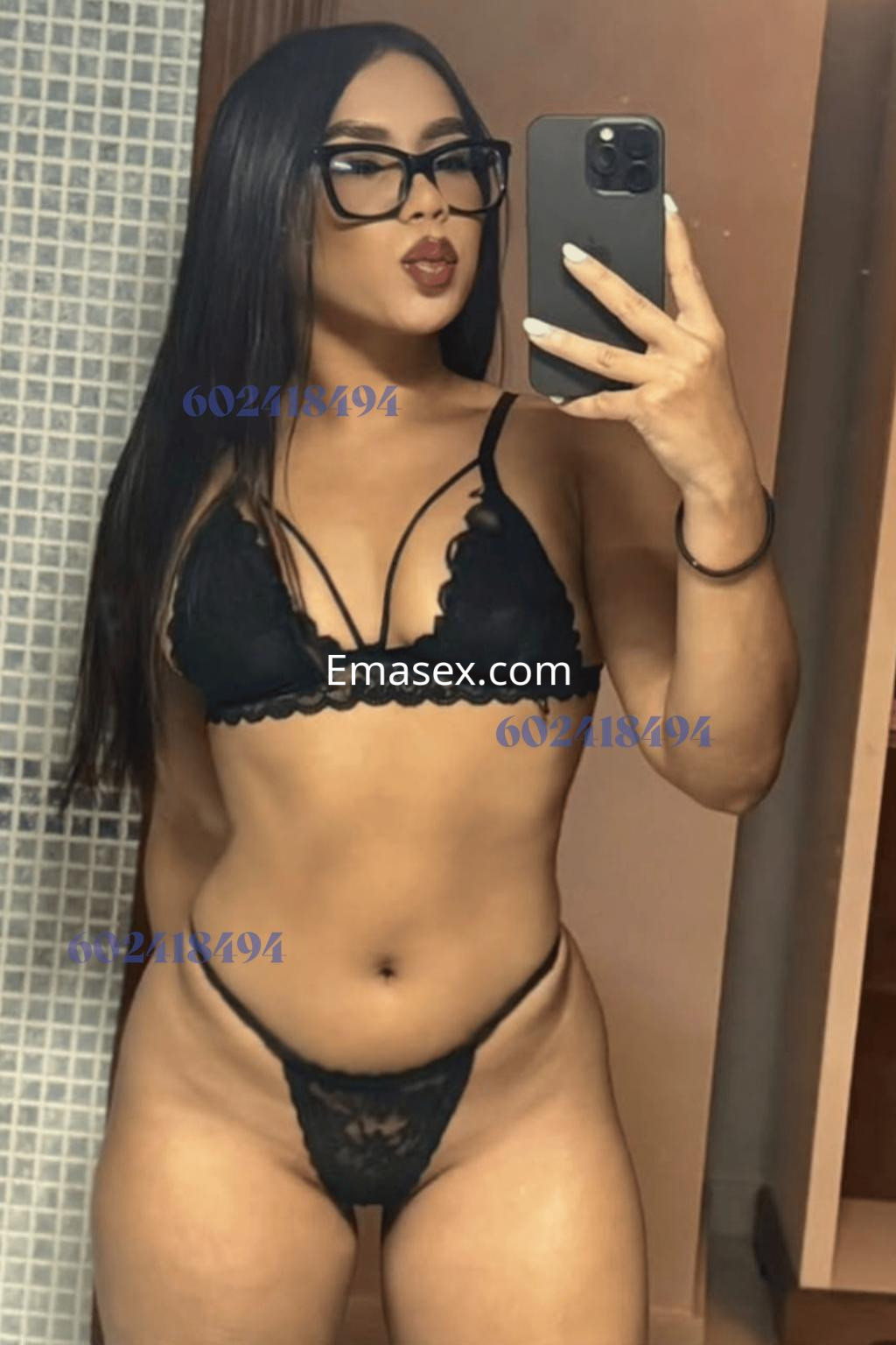 Puta en Córdoba con cabello largo y oscuro, luciendo un conjunto de lencería negra mientras se toma una selfie en el espejo.