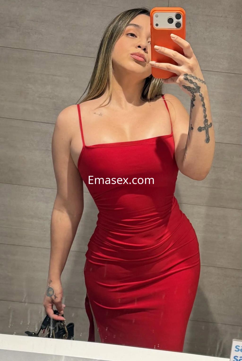 La puta en Burgos posa en un espejo con un vestido rojo ceñido que acentúa su figura y su cabello lacio.