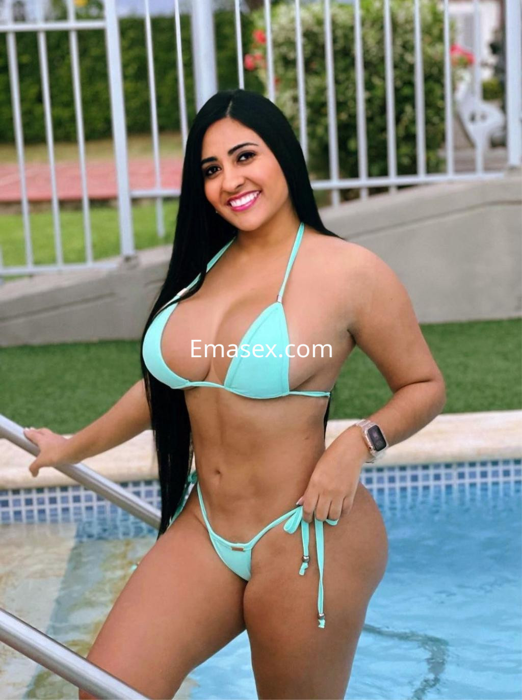 Escort en Vitoria, luciendo un bikini celeste mientras sonríe y posa junto a una piscina.