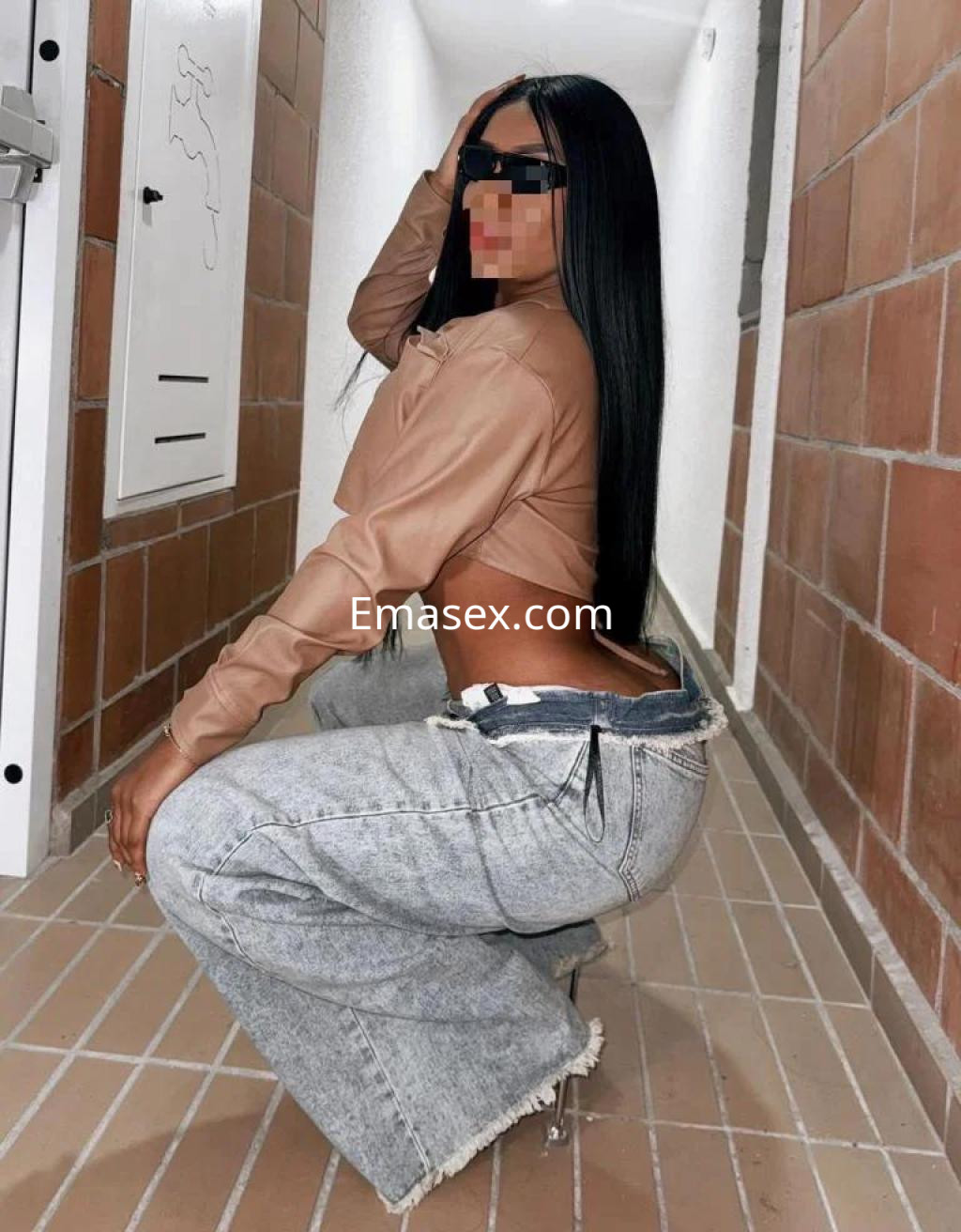 Puta con blusa de cuero marrón y pantalones de mezclilla en un pasillo de edificio en Murcia.