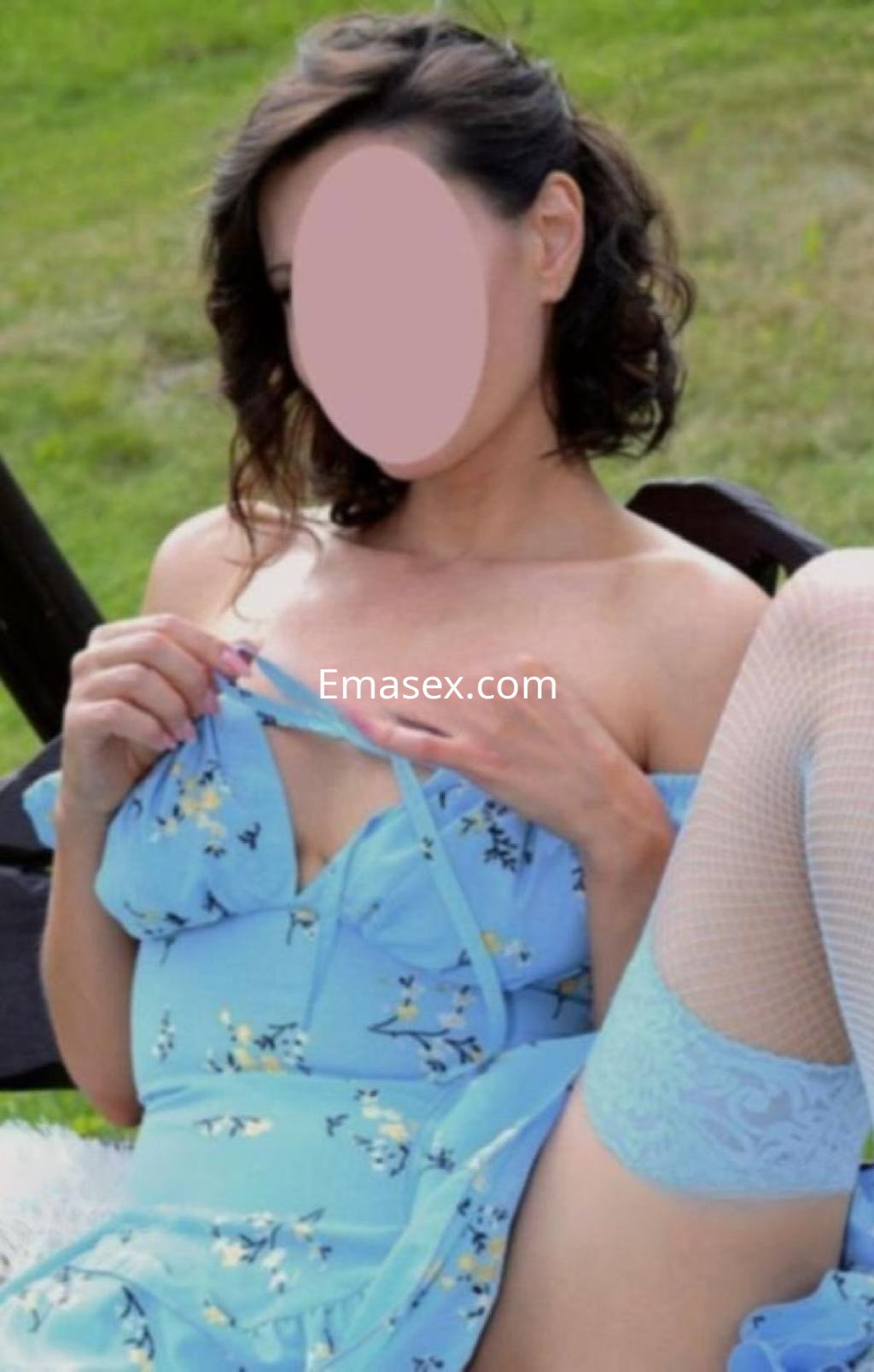 Puta en Valladolid luciendo un vestido azul con flores, en un entorno natural y mostrando un gesto provocador.