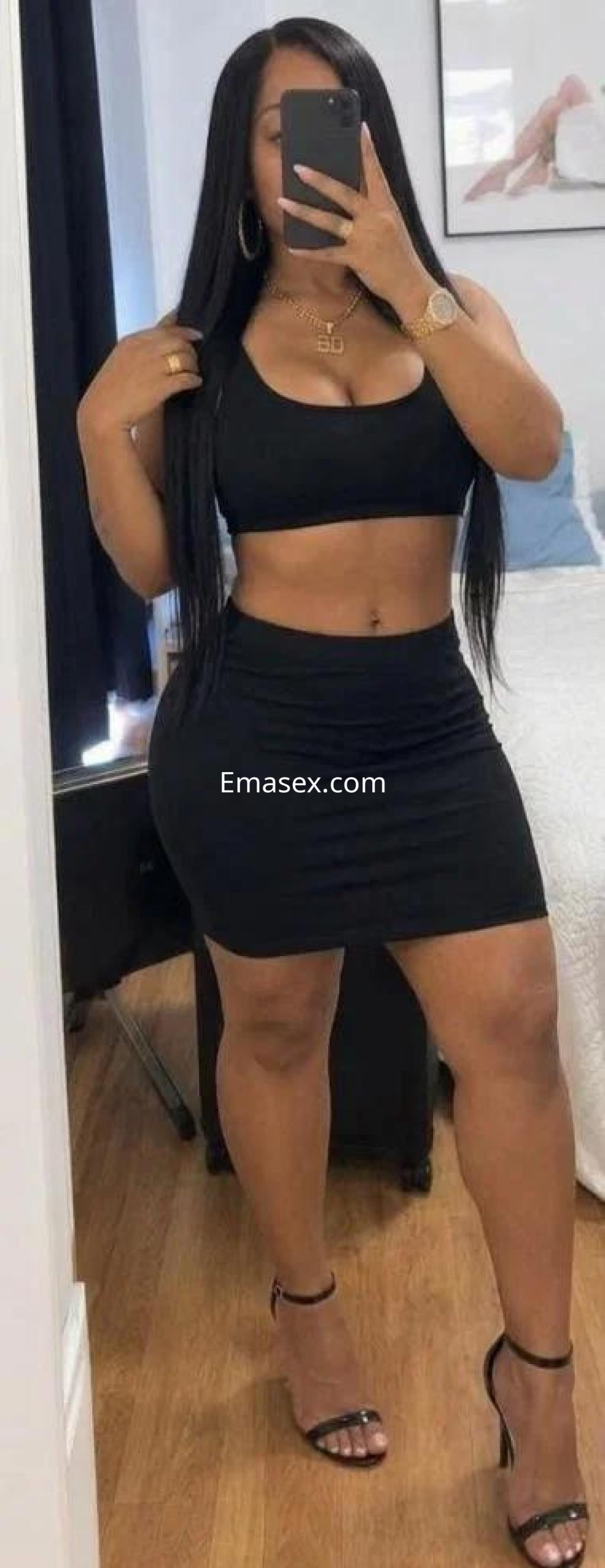 La escort en Tenerife viste un conjunto negro de top y falda corta, complementado con tacones y cabello largo.