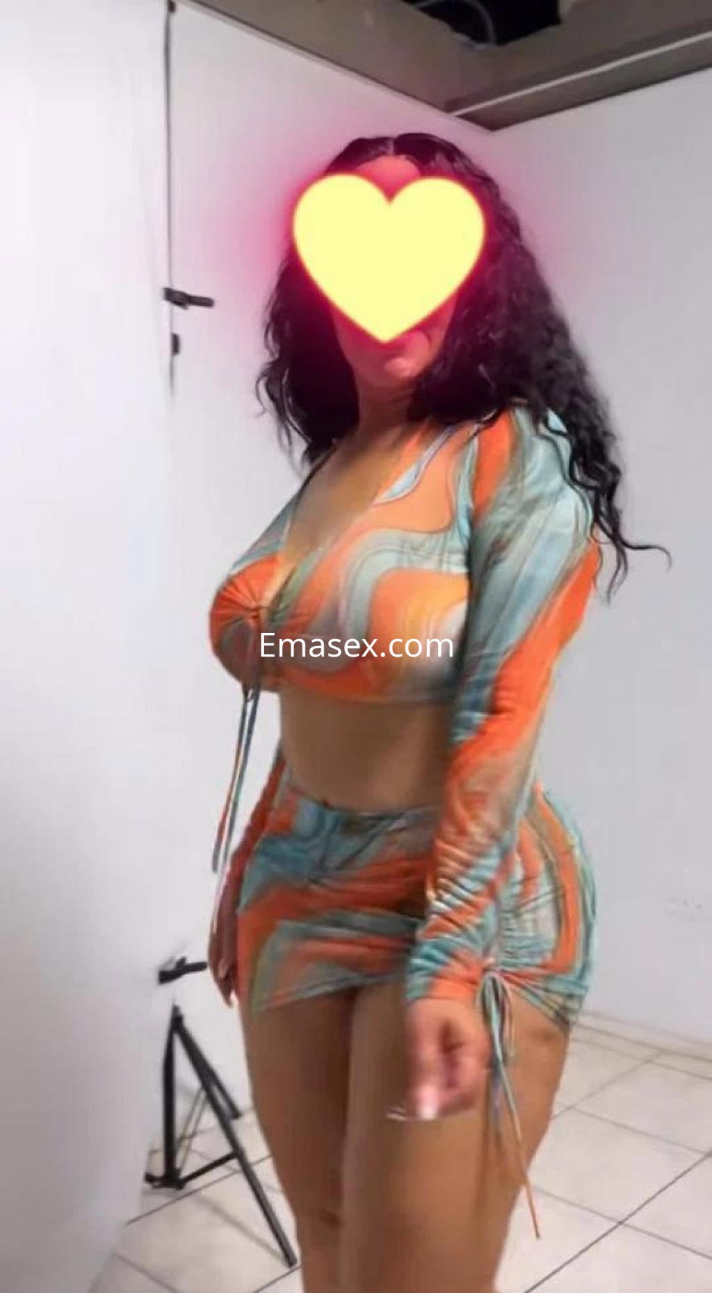 Escort en Valladolid luciendo un conjunto de dos piezas de colores vibrantes, con cabello rizado y sonrisa.
