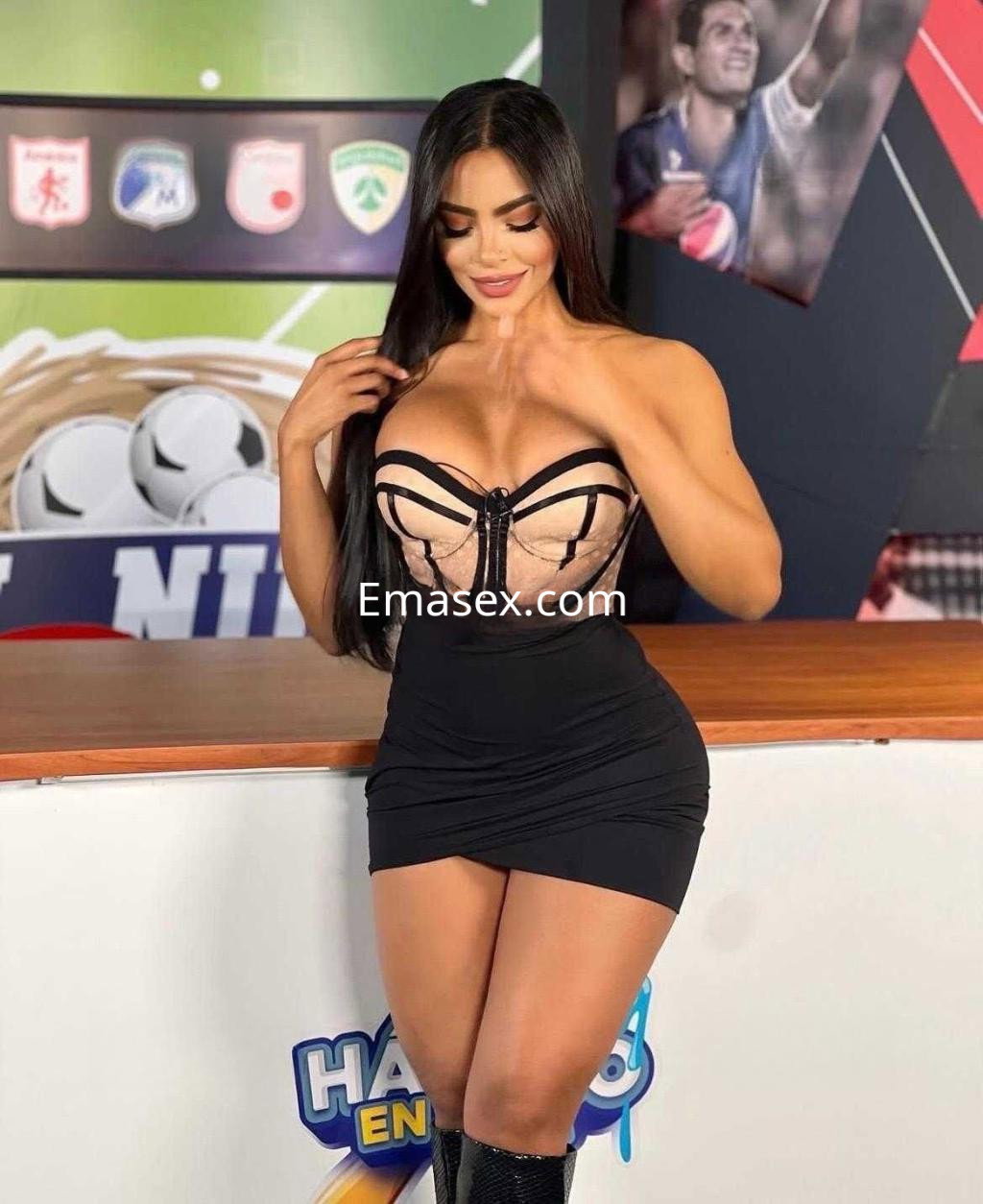 Escort en León con cabello largo y lacio, vistiendo un vestido negro ajustado y un corset de encaje.